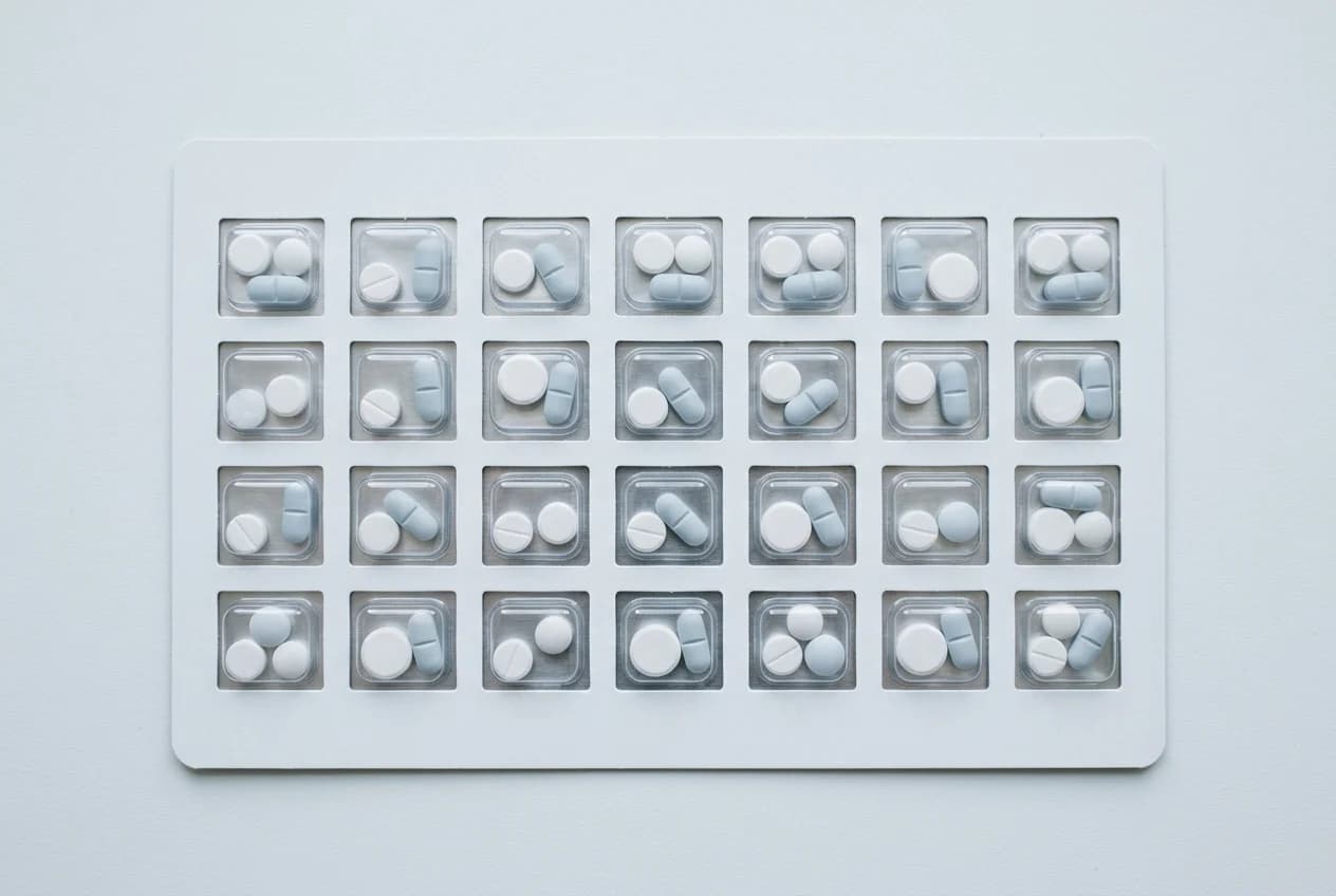 A weekly medication organiser laid flat, each dose sealed in its own compartment across seven columns