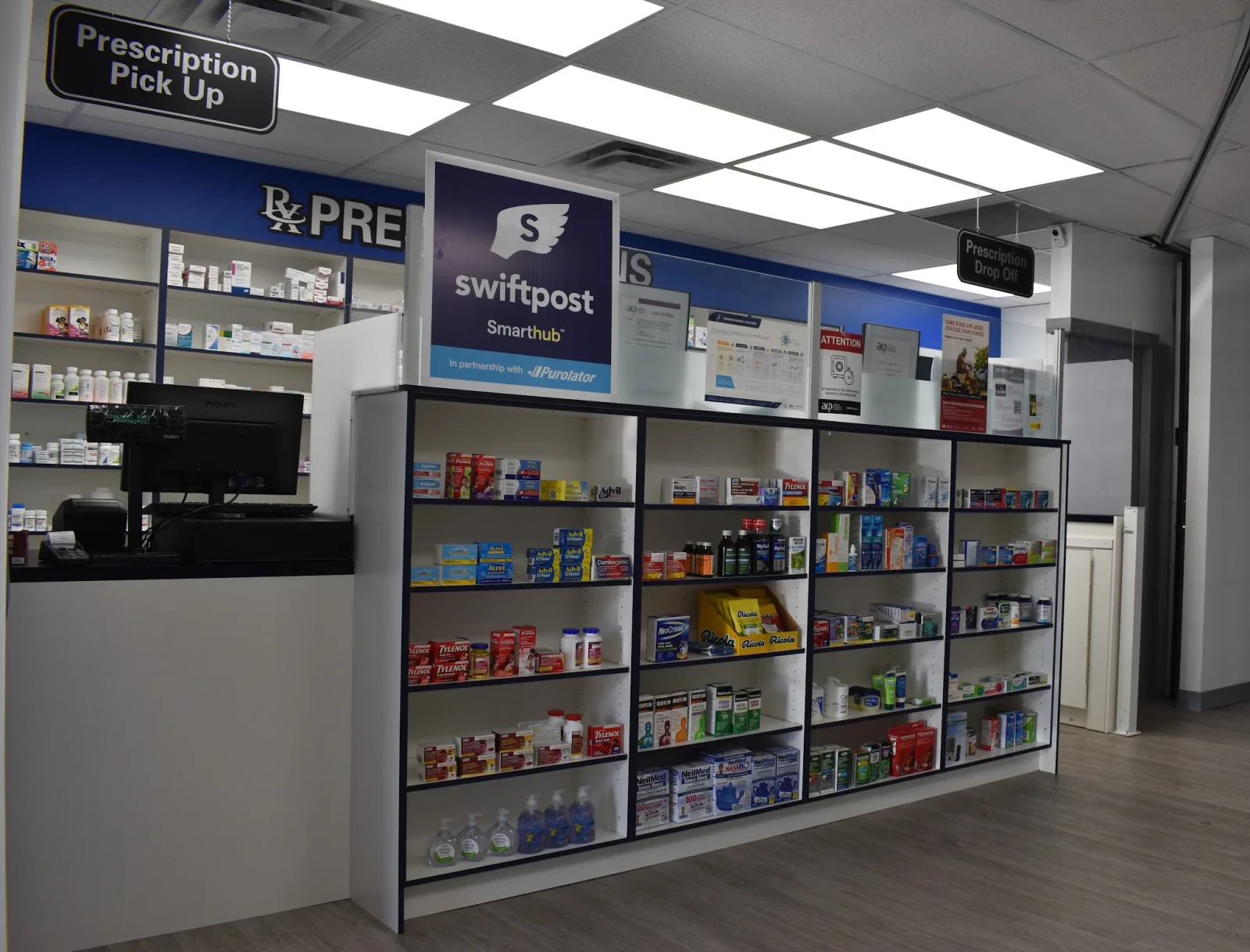 The prescription counter inside Edgemont Family Pharmacy, with the pick-up and drop-off signs above it