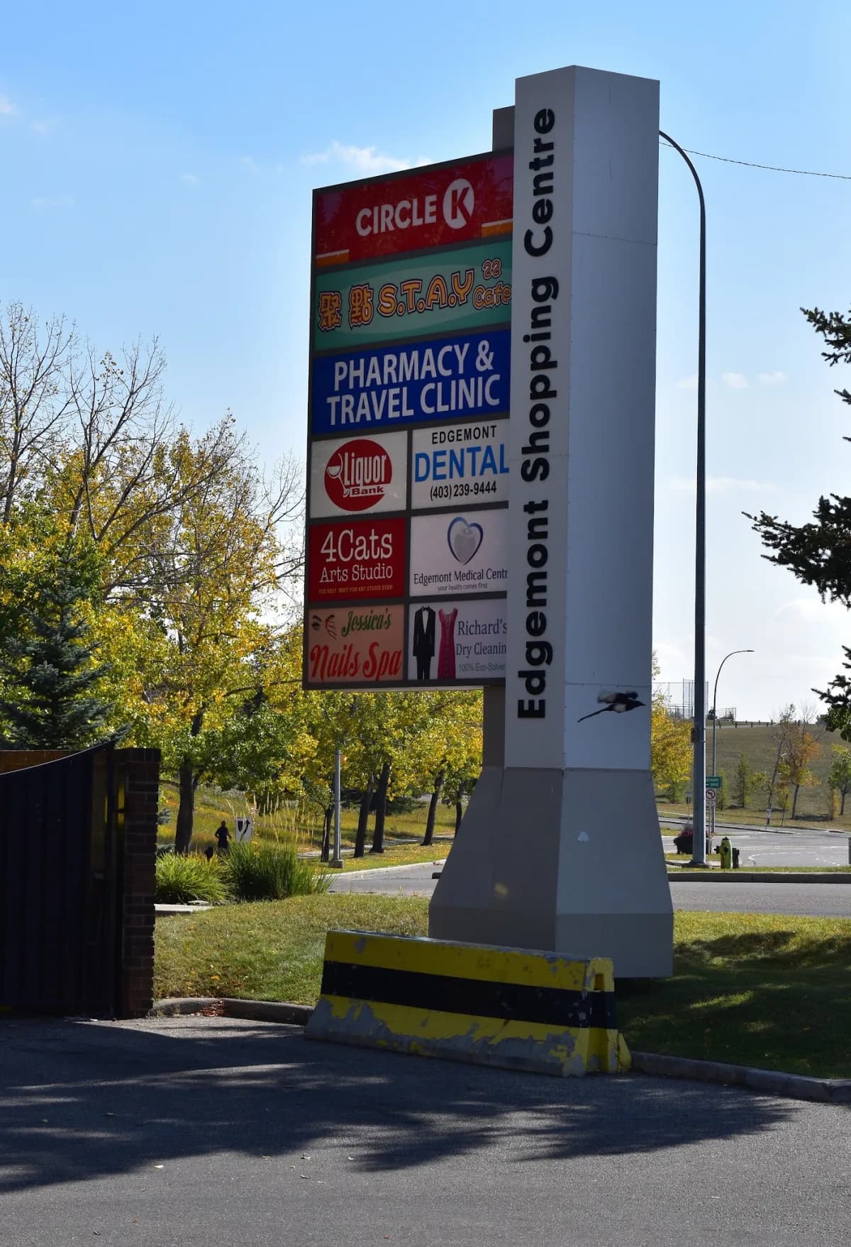 The Edgemont Shopping Centre sign at the road, with the pharmacy and travel clinic panel