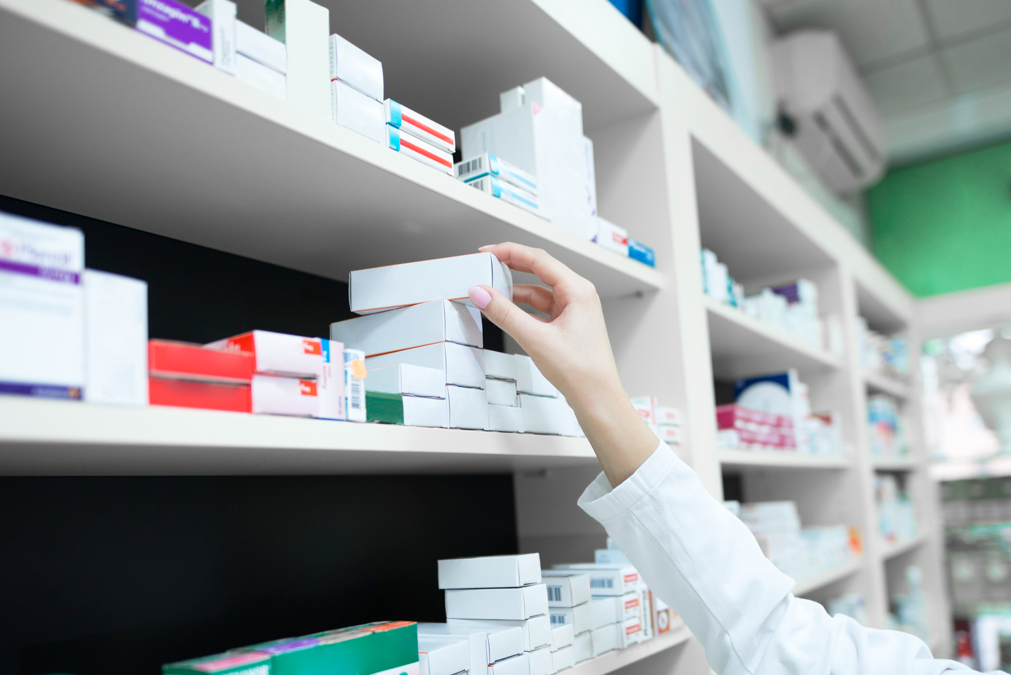 Pharmacist taking a medicine box from the pharmacy shelf